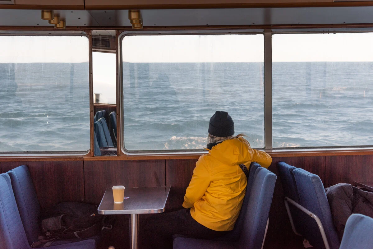personne en veste jaune assise dans un bateau et regardant par la fenêtre