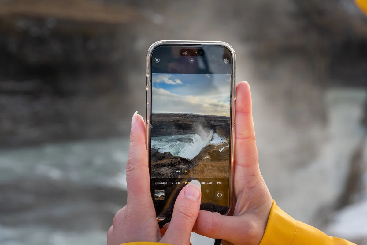 une main tient un téléphone affichant une photo de cascade
