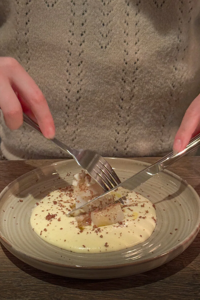 une personne coupe un plat en sauce avec ses couverts