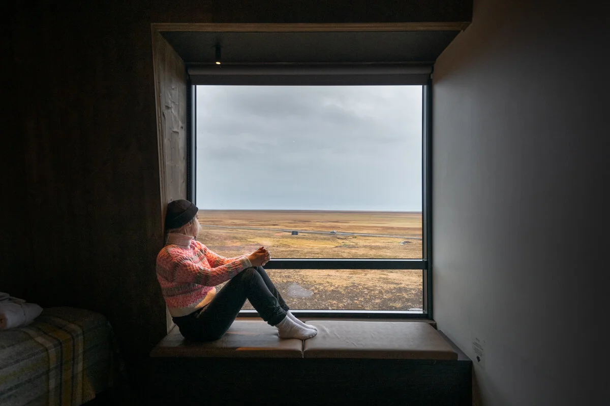 une personne assise sur un rebord de fenêtre regarde le paysage